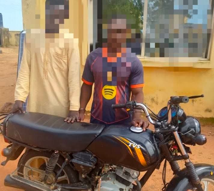 Police officers escort two handcuffed men away from an angry crowd in Niger State, illustrating the intervention to prevent mob justice over motorcycle theft allegations.