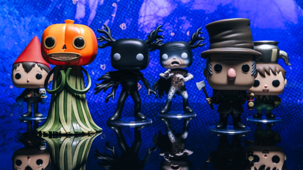 Funko Pop! figures from Over the Garden Wall displayed on a wooden shelf with autumn leaves in the background.