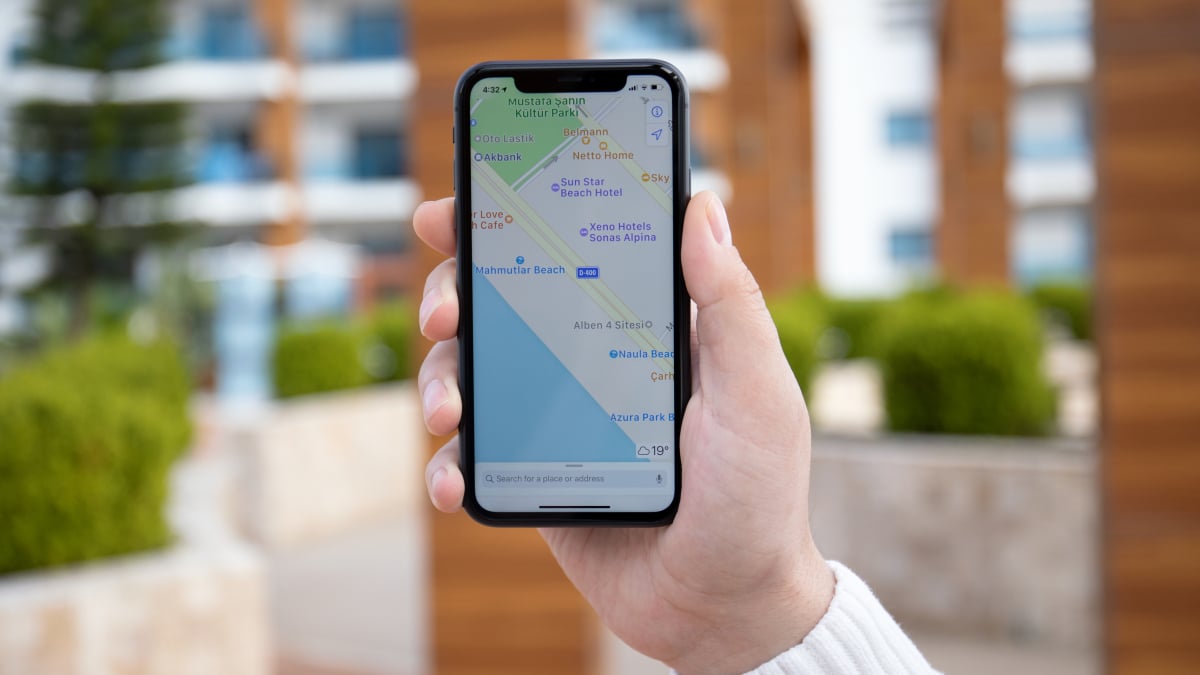 A smartphone on a desk showing Apple Maps with subtle sponsored listings in the interface.