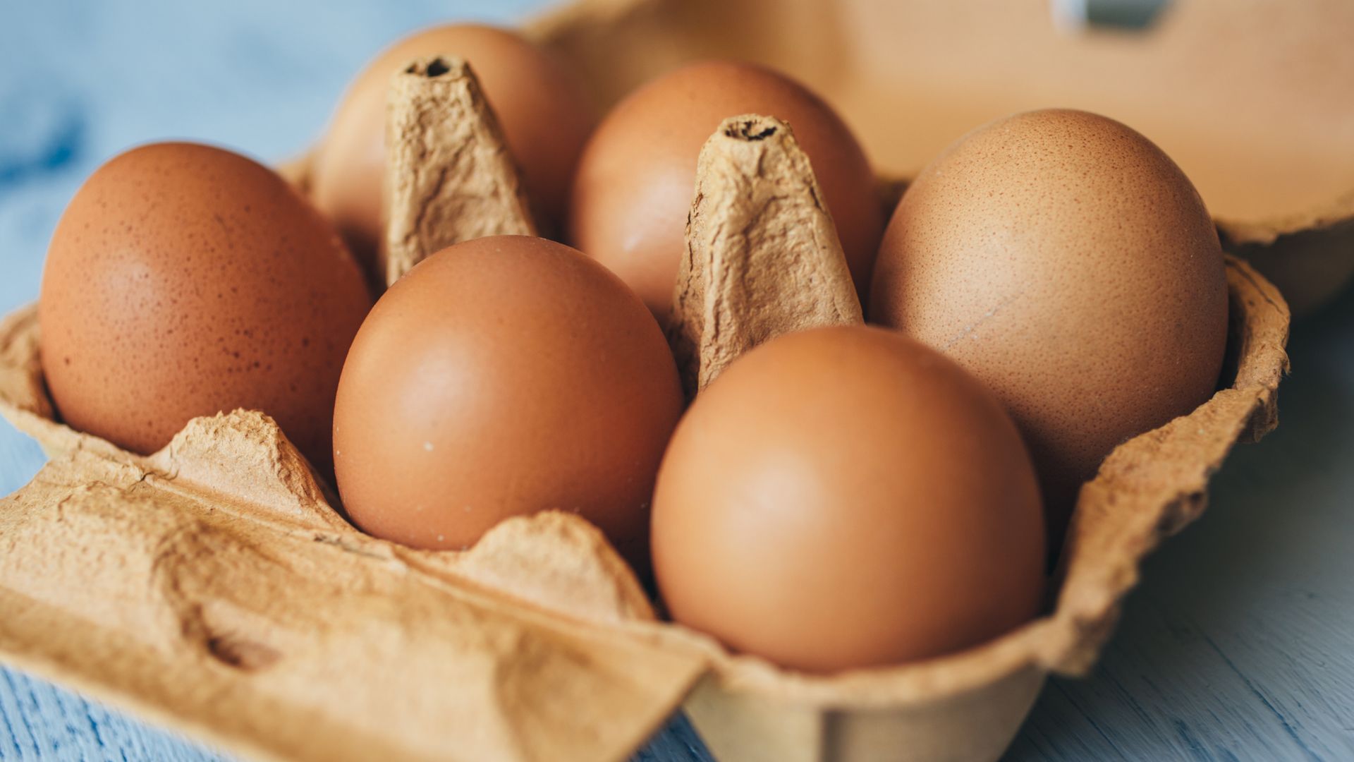 Close-up of a cracked brown egg on a white plate, representing food safety concerns.
