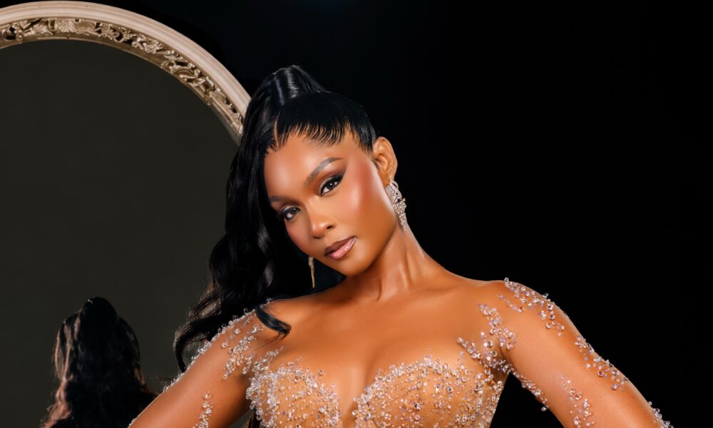 A custom bridal couture gown by Veekee James featuring a sheer illusion corset, crystal embellishments, and a sweeping chapel train, displayed elegantly on a mannequin.