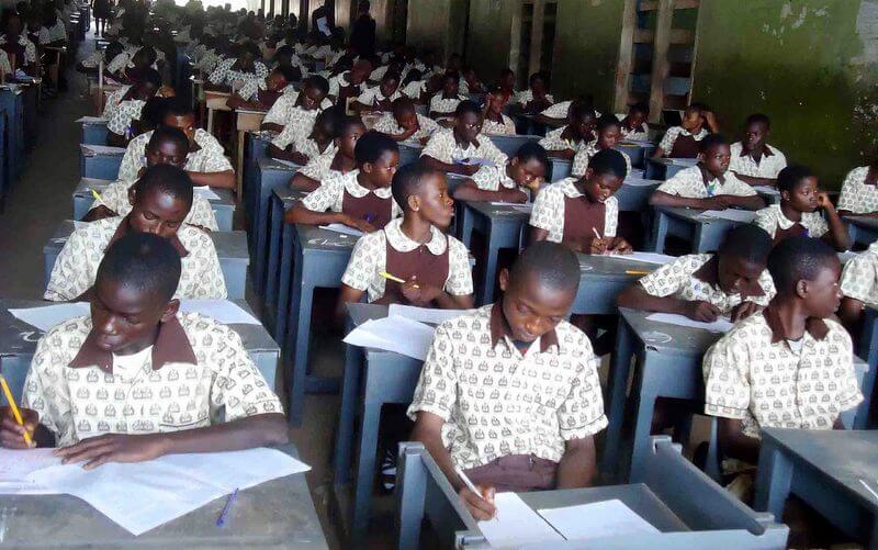 Nigerian students writing examinations in a bright classroom with academic achievement displays