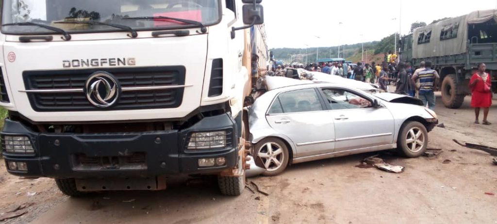Emergency workers at a multi-vehicle crash site on the Enugu-Onitsha Expressway, with wrecked cars and responders in safety gear