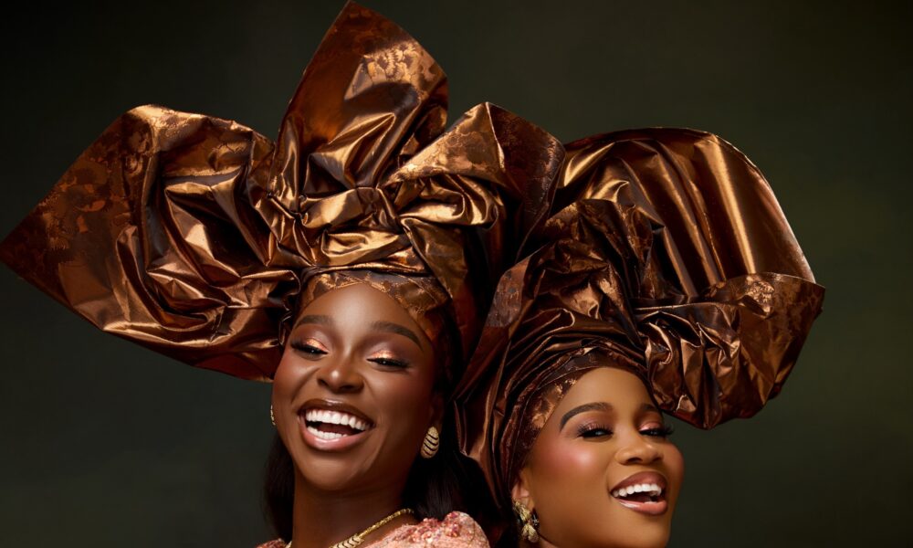 Two women in peach sequin lace and bronze‑gold headties embodying vintage Nigerian glamour at a wedding reception.