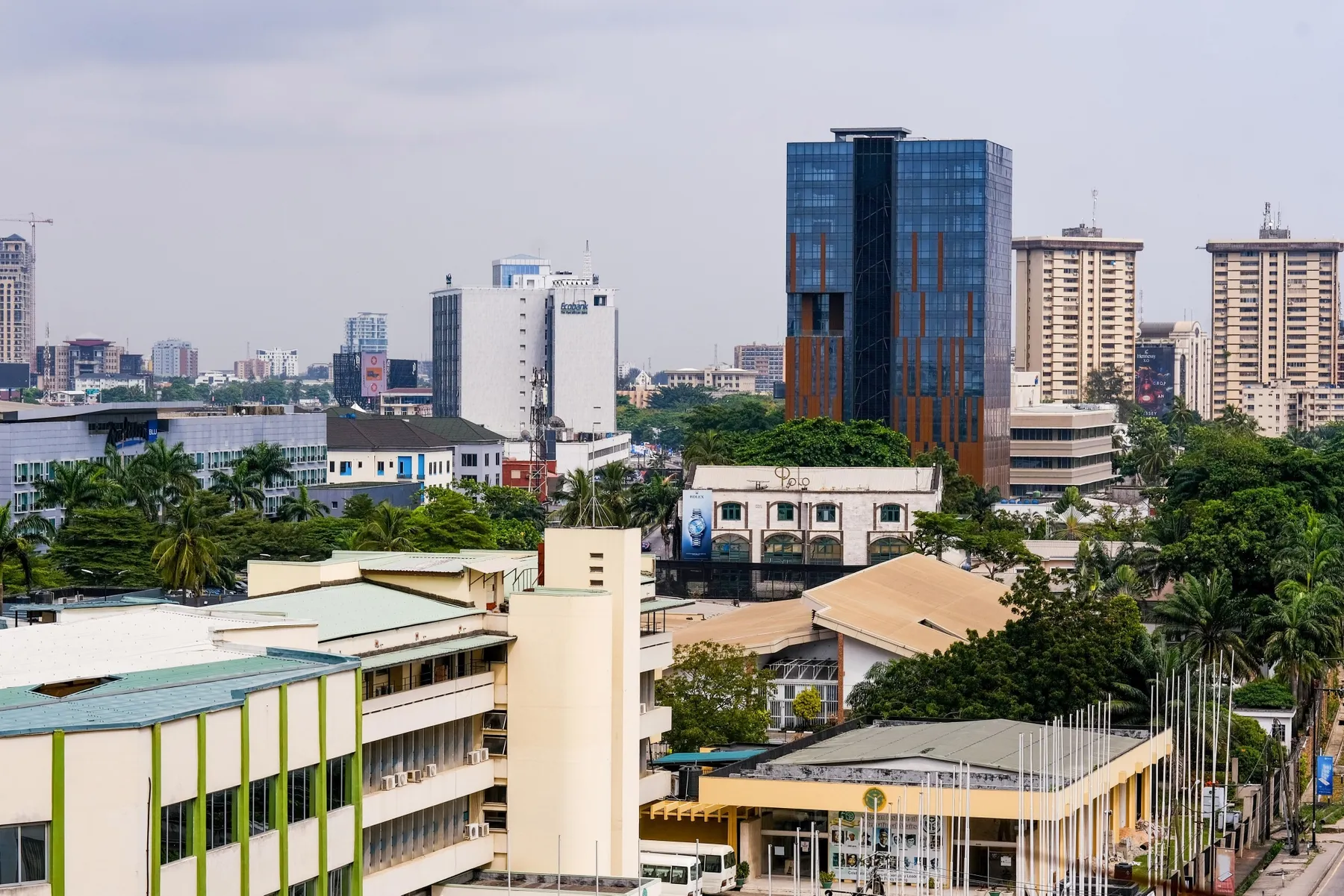 A telecommunications tower against the Lagos skyline with informal market traders in the distance, symbolising Nigeria's uneven economic growth
