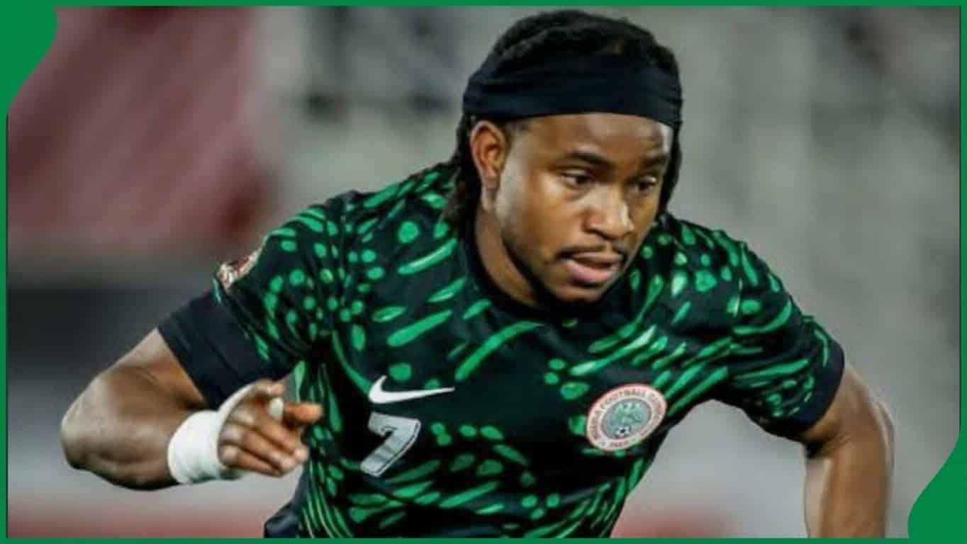 Nigerian footballer in green and white kit playing on an African football pitch during AFCON qualifiers