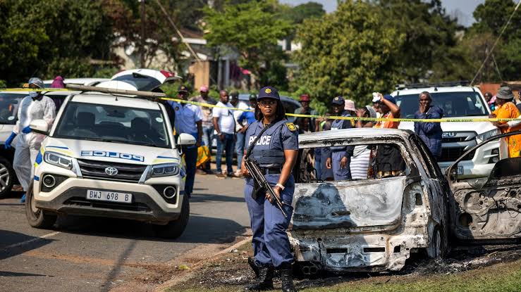 Police patrol cars on a night‑time Johannesburg street, indicating a manhunt in progress.