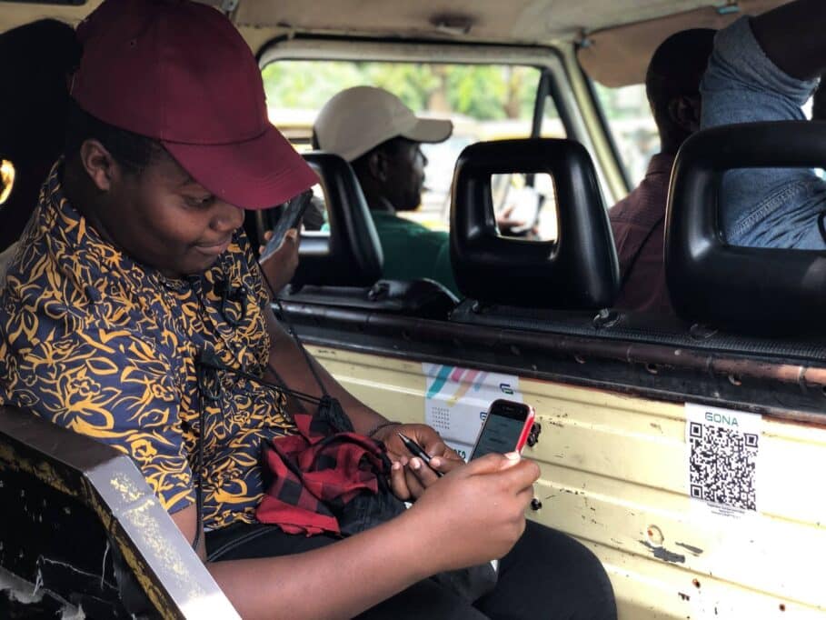Interior of a Lagos danfo bus with a QR code sticker on the window, symbolising the failed cashless transport experiment