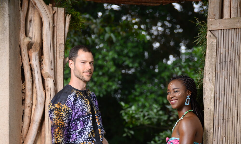 A happy Ghanaian-American couple and their child enjoying a relaxed morning on the veranda of their Lagos home, surrounded by lush greenery and modern architecture.