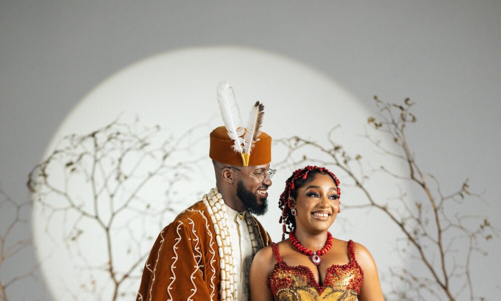 A stylish Nigerian traditional wedding couple in elegant attire under decorative arches
