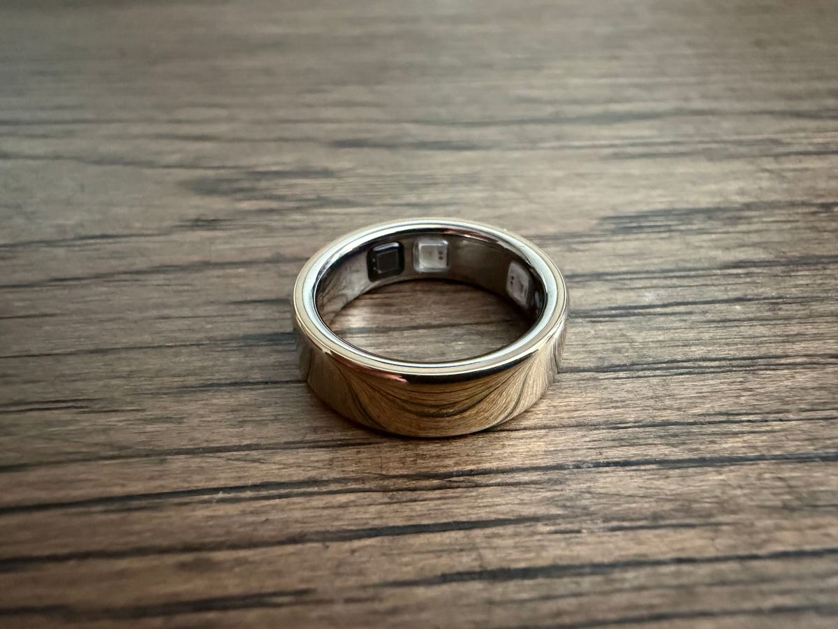 Oura smart ring on a steel surface with a blurred stock ticker behind it, suggesting an IPO filing