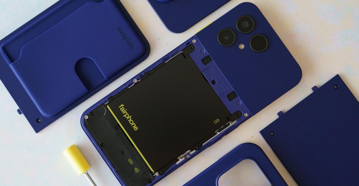 Fairphone 6 Plus phone with its back cover removed next to a screwdriver on a wooden desk.