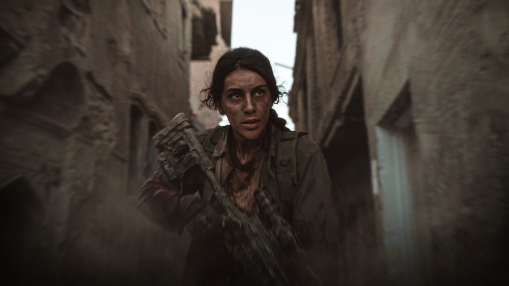 Female Peshmerga sniper aiming a rifle in mountainous landscape at dawn