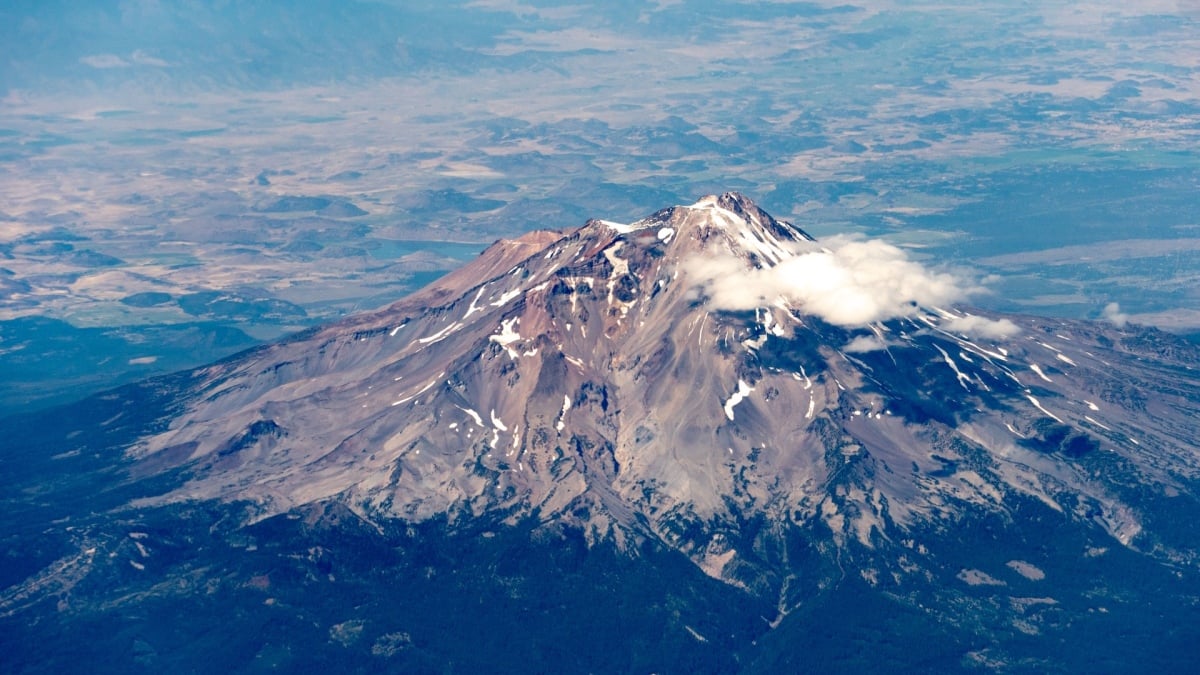 Mt. Shasta landscape with a backpack and smartphone on rocks under sunrise light