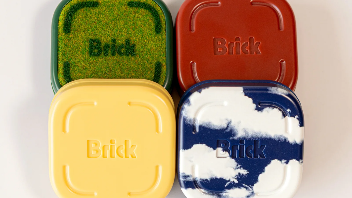 Brick screen‑time lock device with four colorful cases on a desk