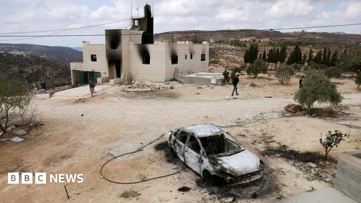 Smoke billowing from a burned home in a West Bank village at dusk