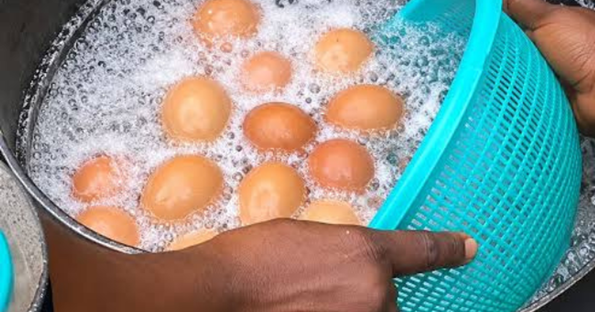 Street vendor selling boiled eggs in a Nigerian market, with a caution symbol indicating possible contamination.