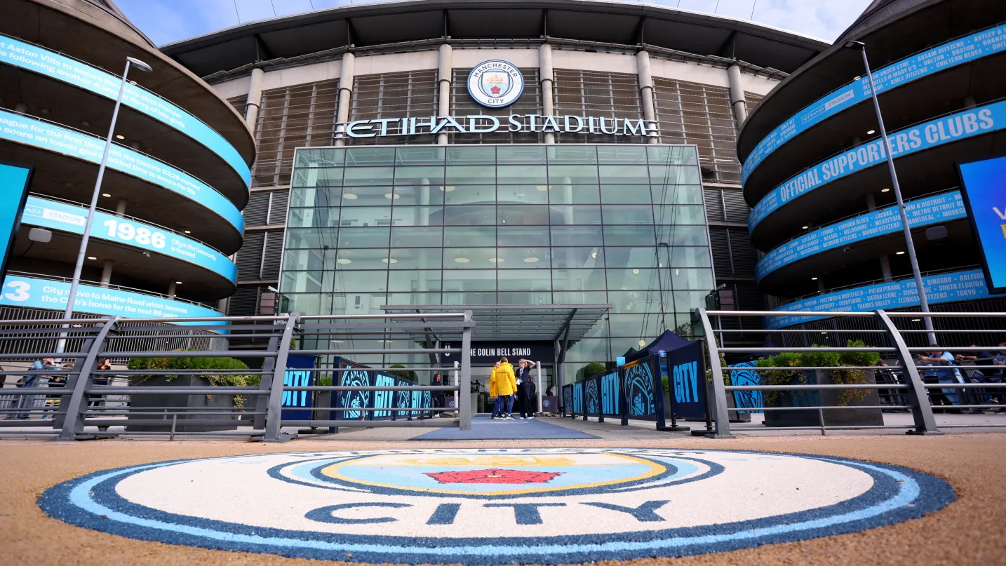 Manchester City stadium illuminated at night with Nigerian fans cheering in blue scarves.