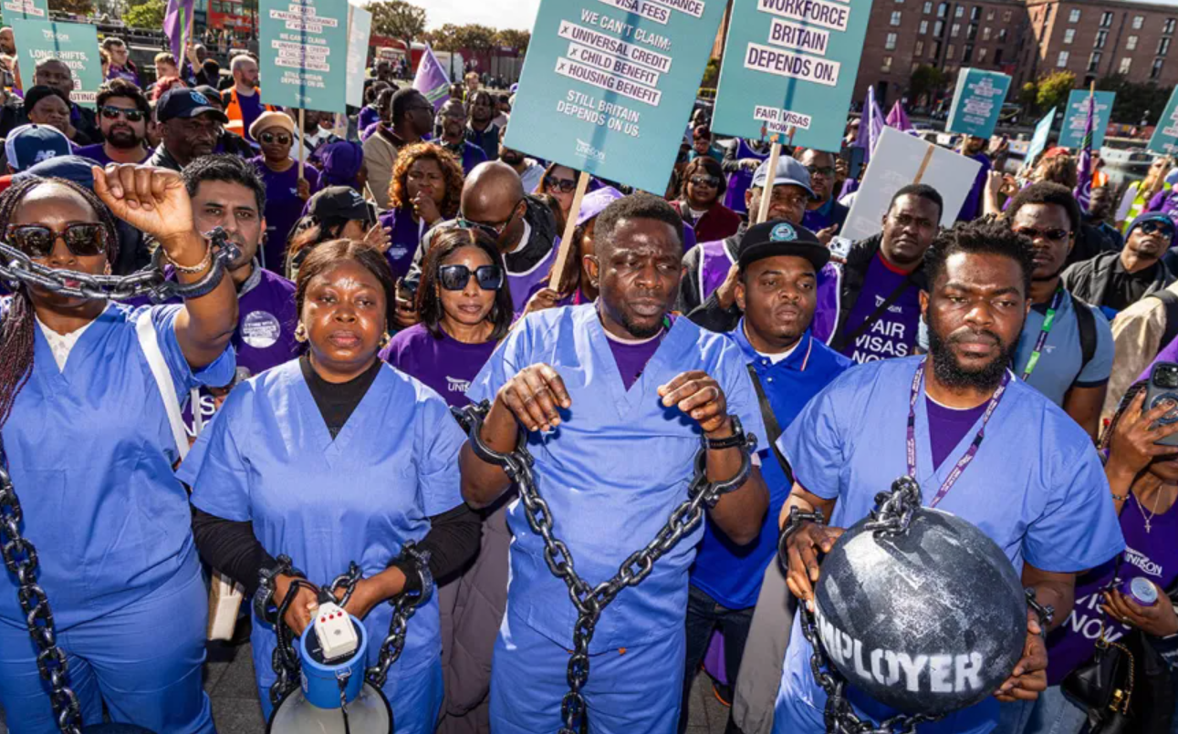 African migrant care workers protesting UK visa reforms in London with symbolic chains