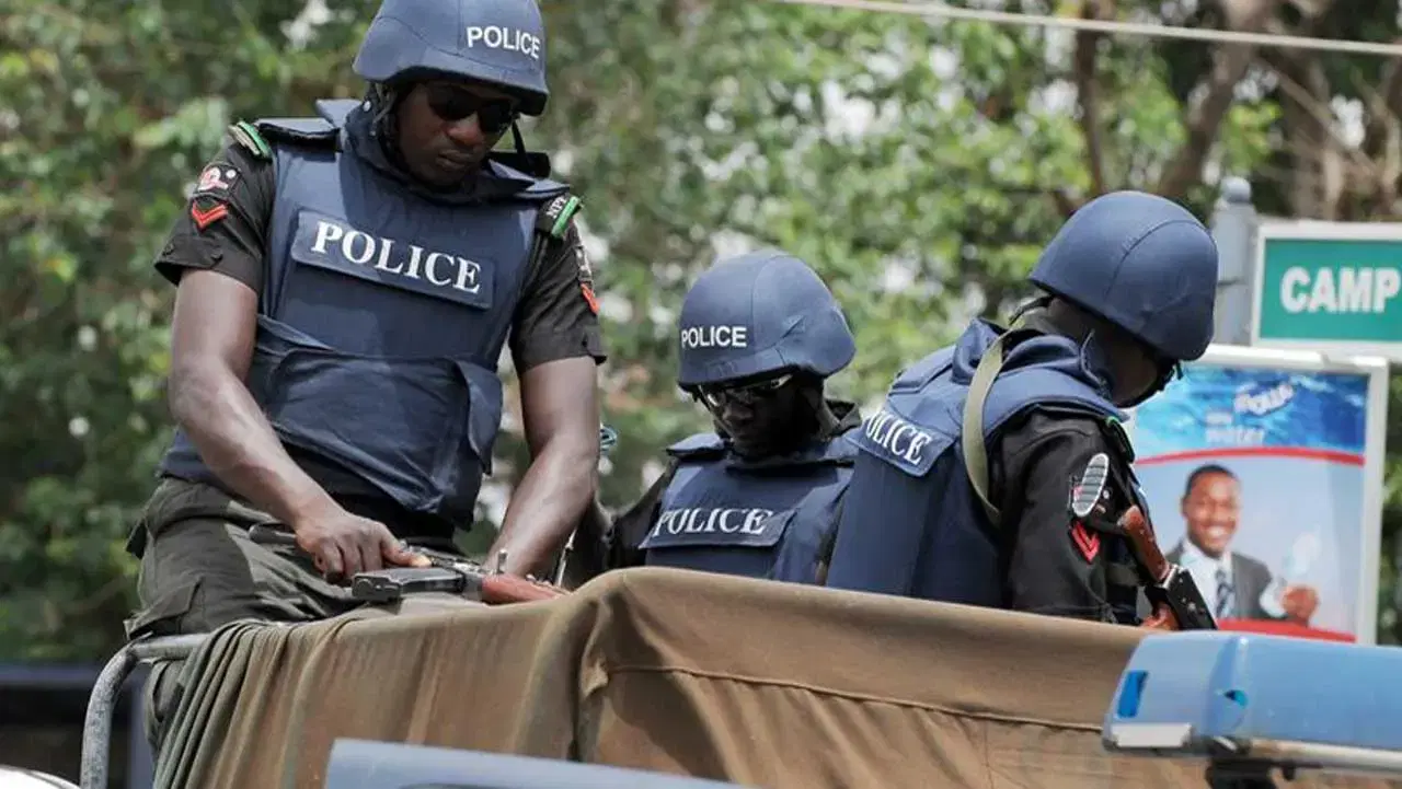 Police patrol car outside a modest house in a Nigerian town, indicating a criminal investigation.