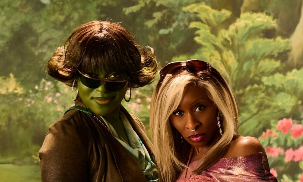 Early‑2000s Nollywood inspired pink and green costumes on a stage with Lagos skyline backdrop