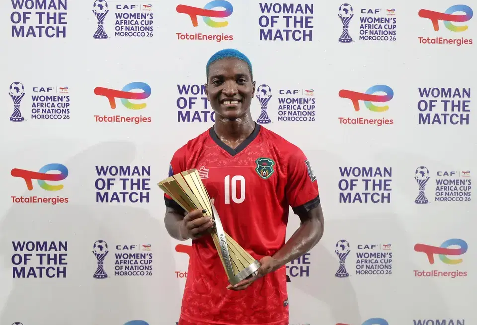 Celebratory female footballer silhouette in a bustling African stadium
