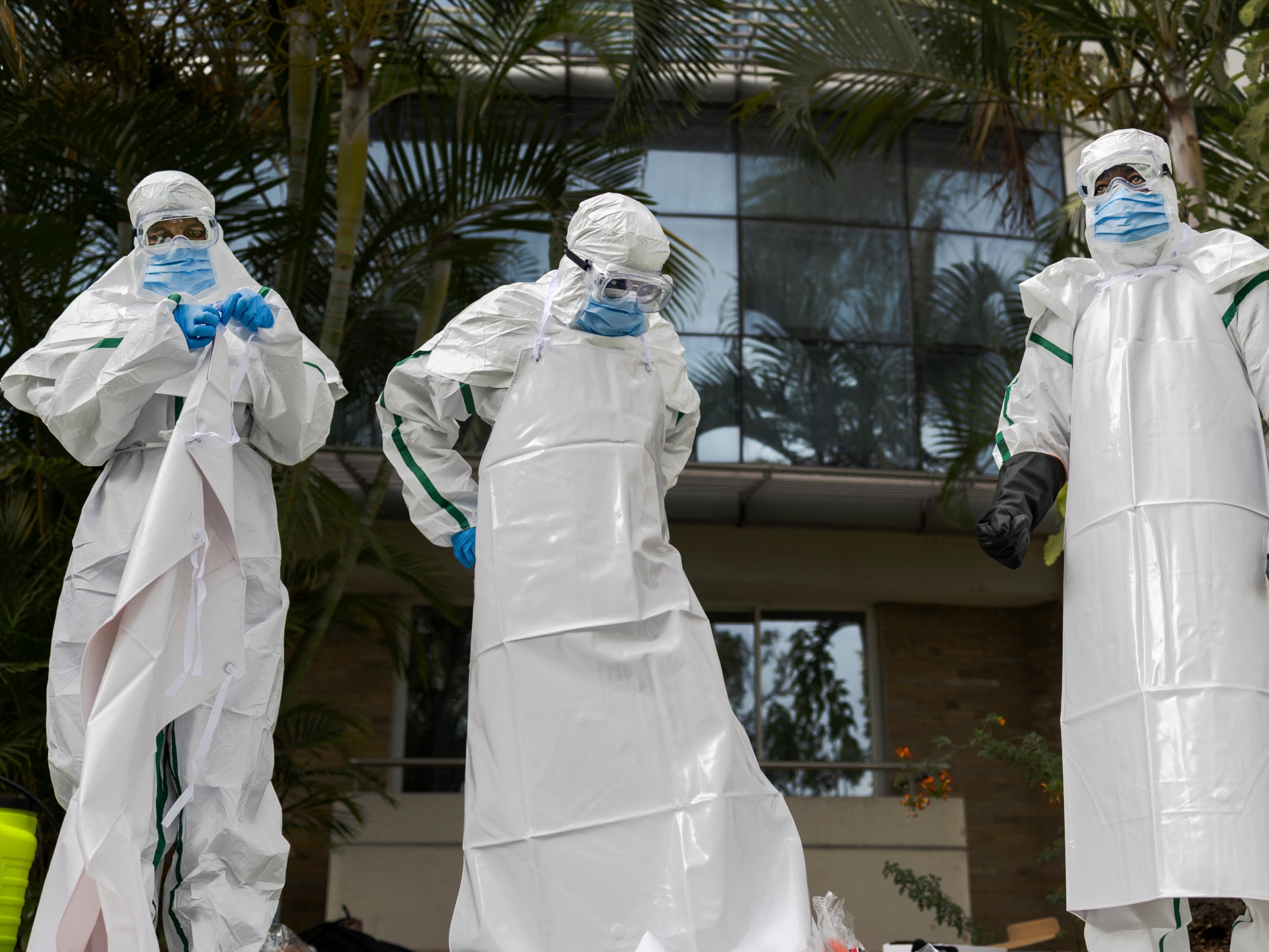 Health workers in PPE beside an ambulance on a Lagos street, symbolising Ebola response efforts.