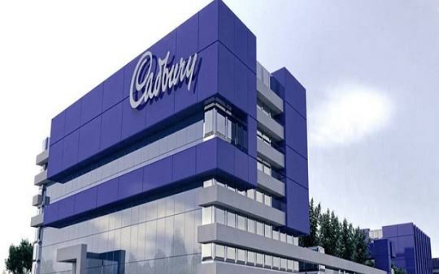 Cadbury Nigeria factory interior with chocolate production lines and Lagos skyline view