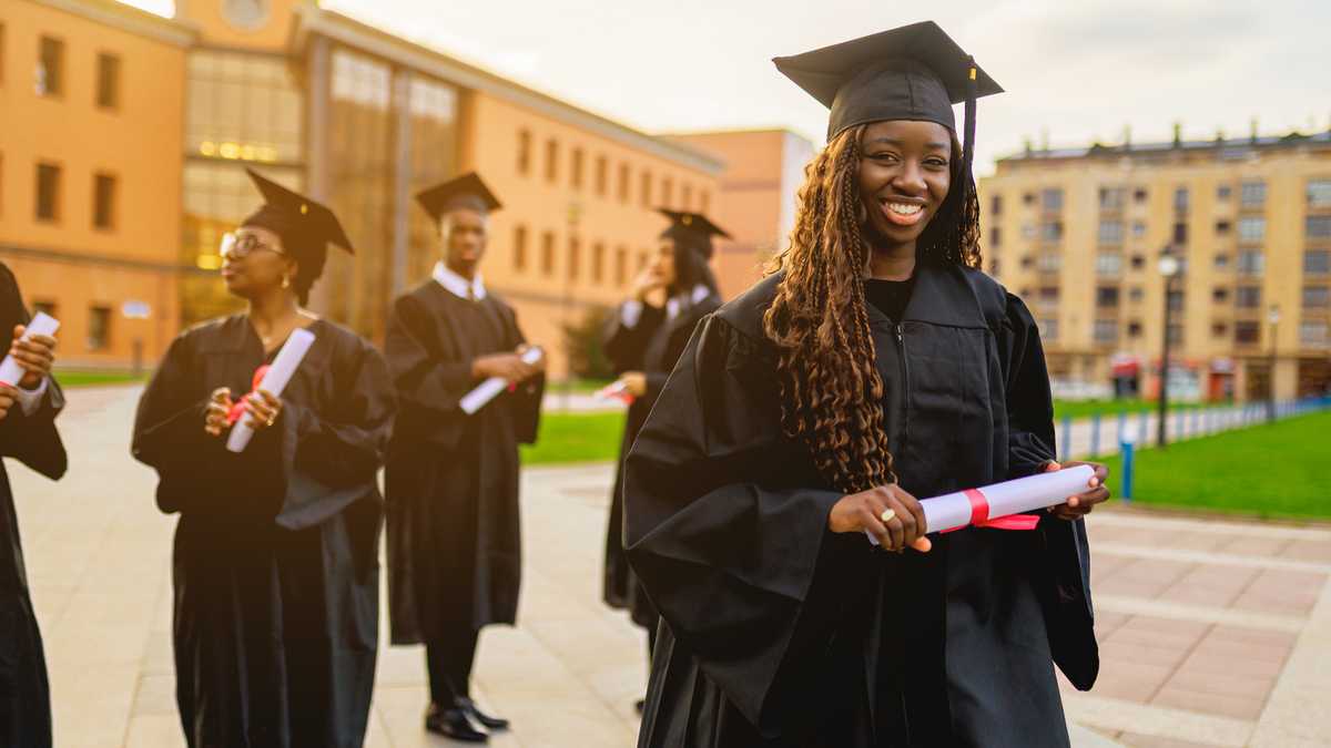 Hand passing a graduation cap with its lining open at a Nigerian university ceremony