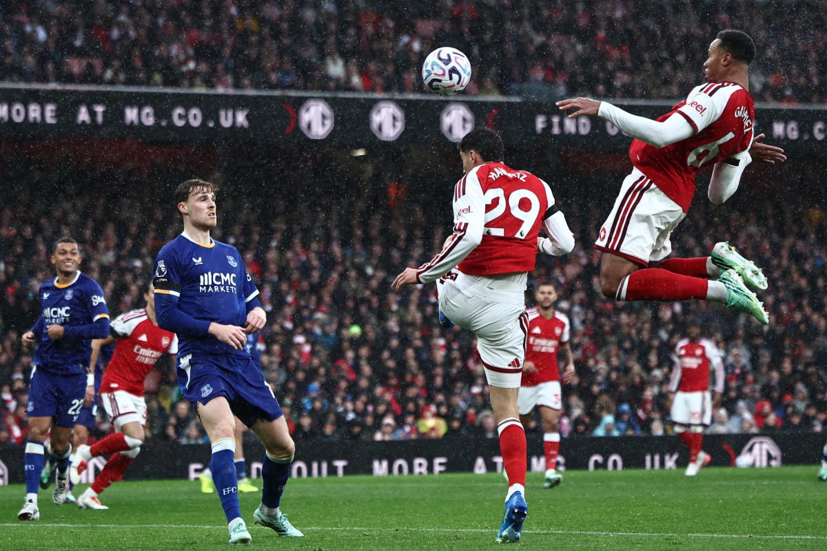 Arsenal and Everton players battling on the pitch with African fans cheering in the stands