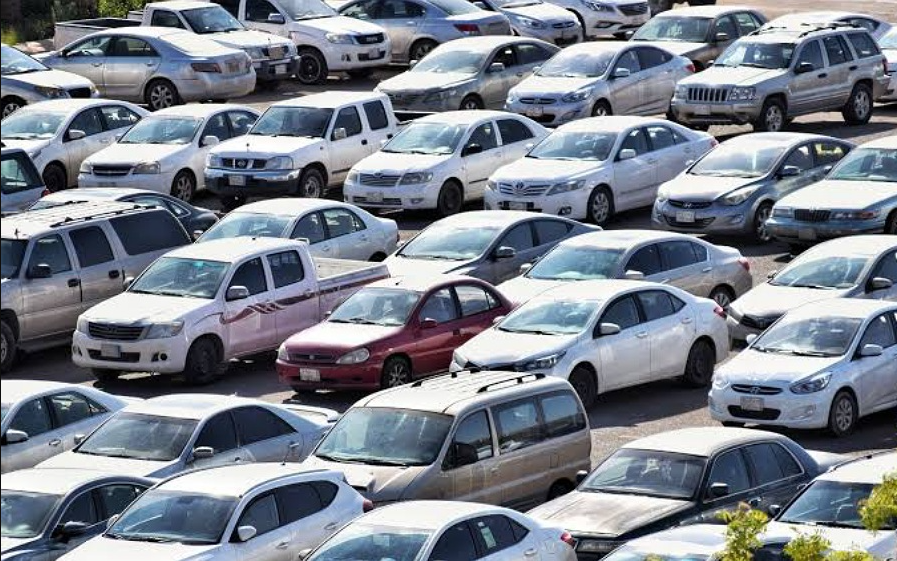 Local Nigerian cars displayed in a showroom with a government building in the background.
