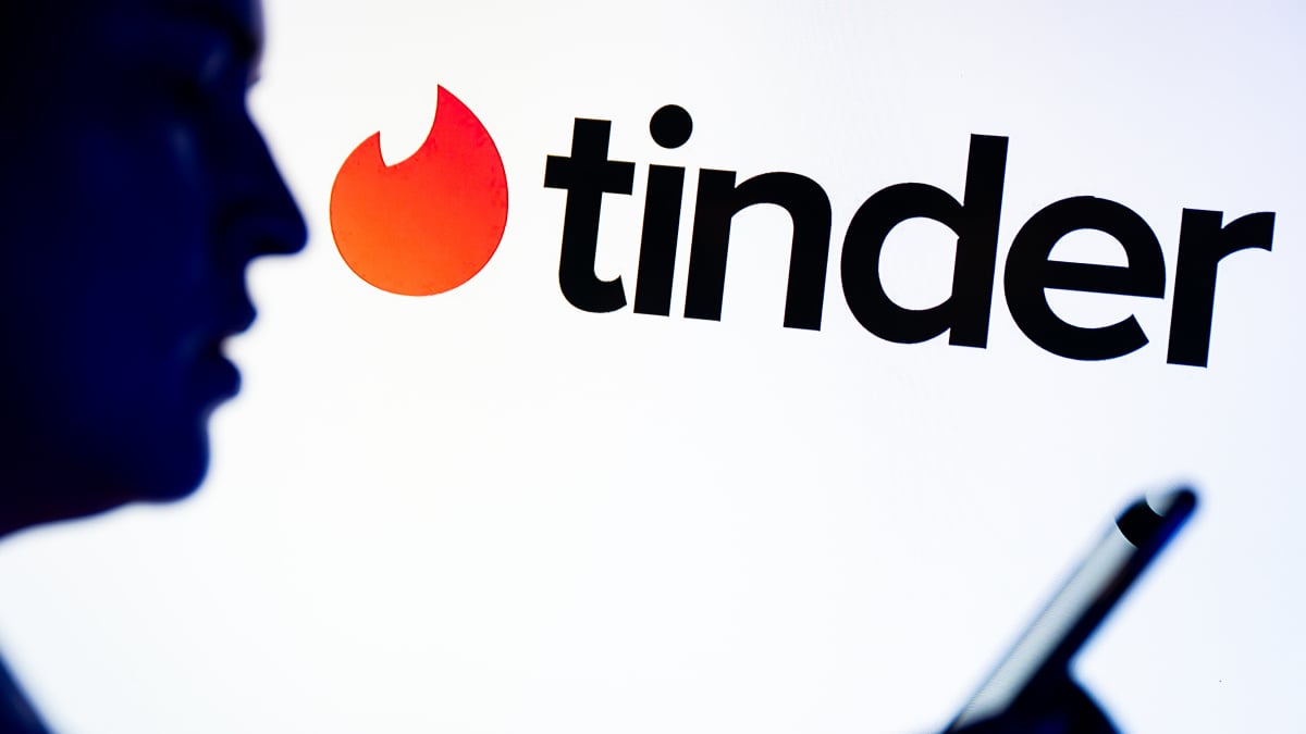 Smartphone showing Tinder interface with warning symbols and abstract code patterns indicating scam detection.