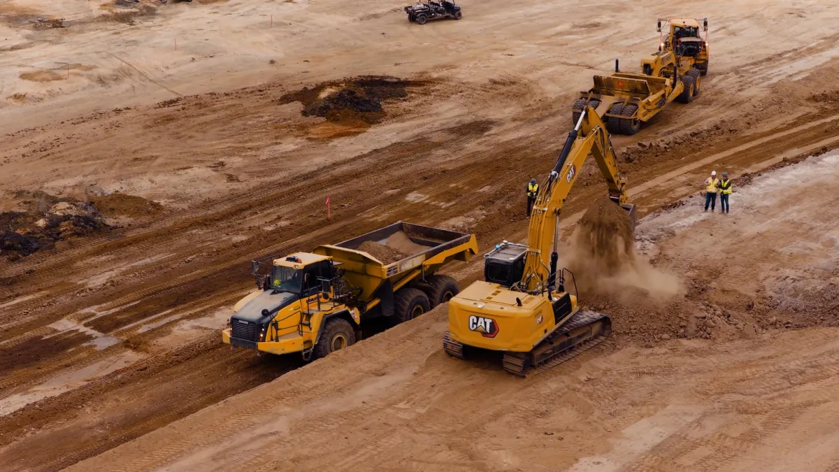 Autonomous excavator operating on a construction site with a city skyline in the background