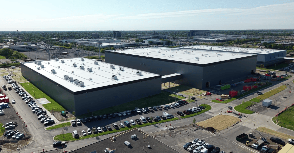 White industrial buildings at GM’s Warren campus with solar panels and EV prototypes.
