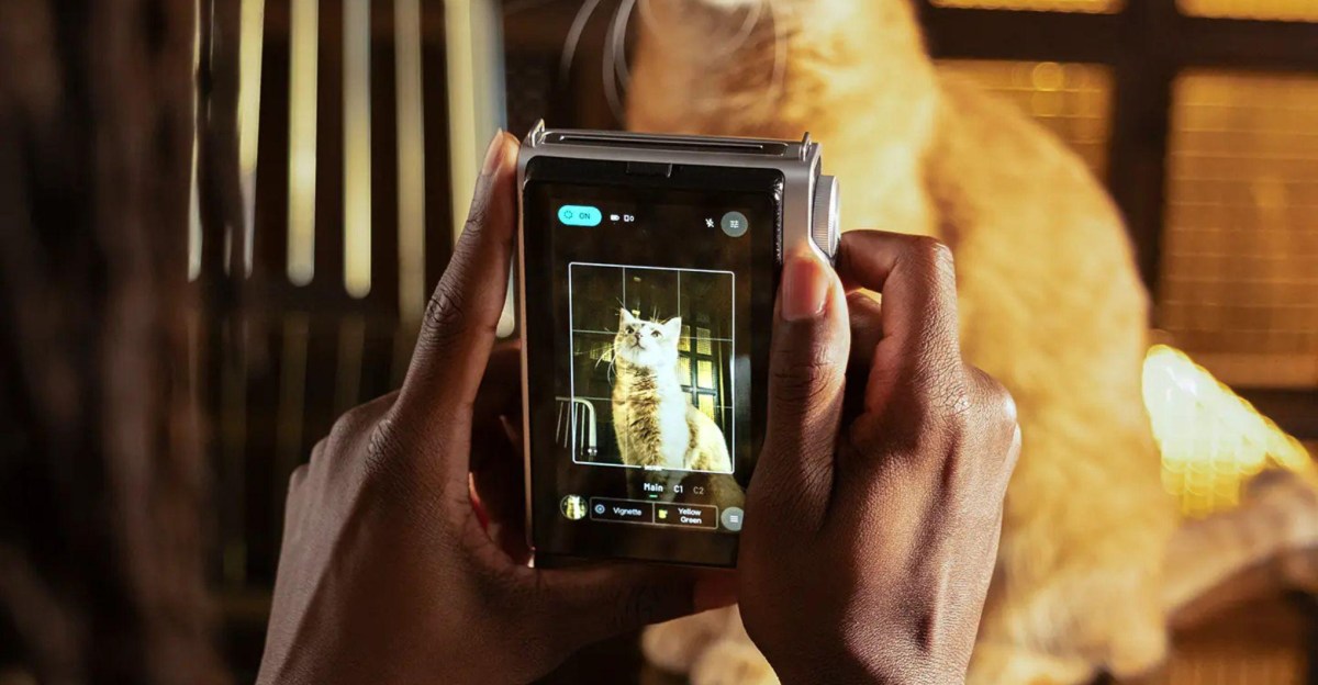 Instax Mini Evo 2 camera with illuminated touchscreen and freshly printed instant photos on a wooden surface