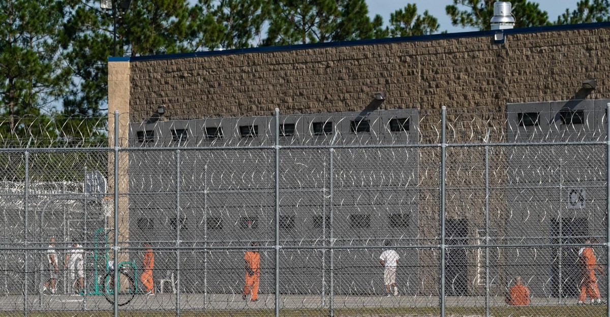 Interior hallway of an ICE detention center with computer equipment visible.